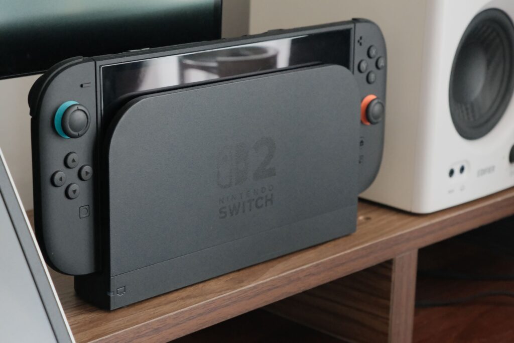 A docked Nintendo Switch 2 unit sits on a wooden shelf.